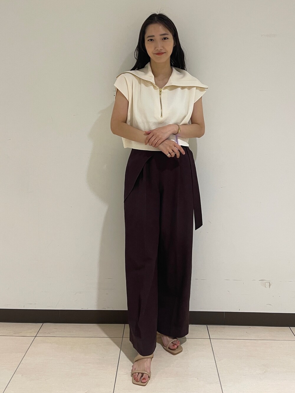 ブラウン系のその他パンツ、ホワイト系のニット/セーター、ベージュ系のサンダルを着用したレディースの春コーディネートの2枚目の写真