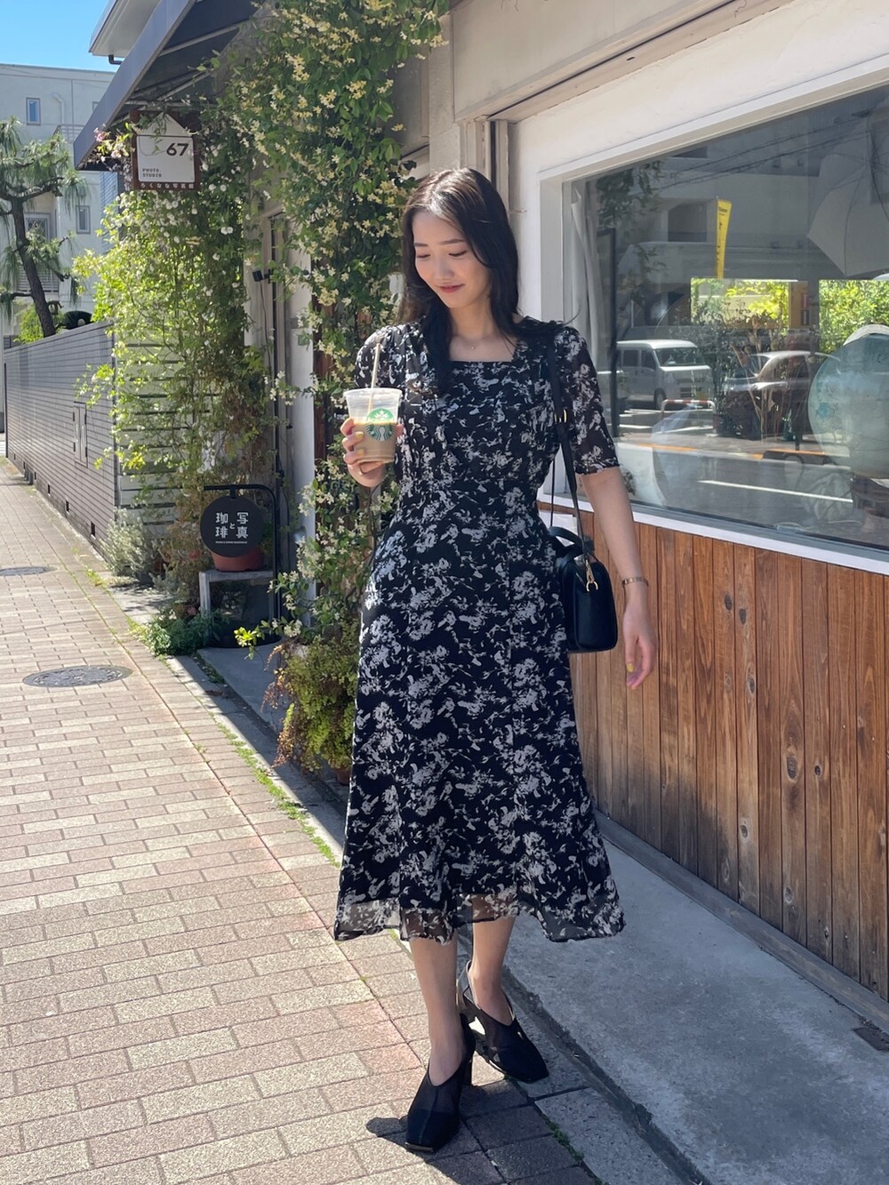 ブラック系のショルダーバッグ、ブラック系のワンピース、ブラック系のパンプスを着用したレディースの春コーディネートの3枚目の写真