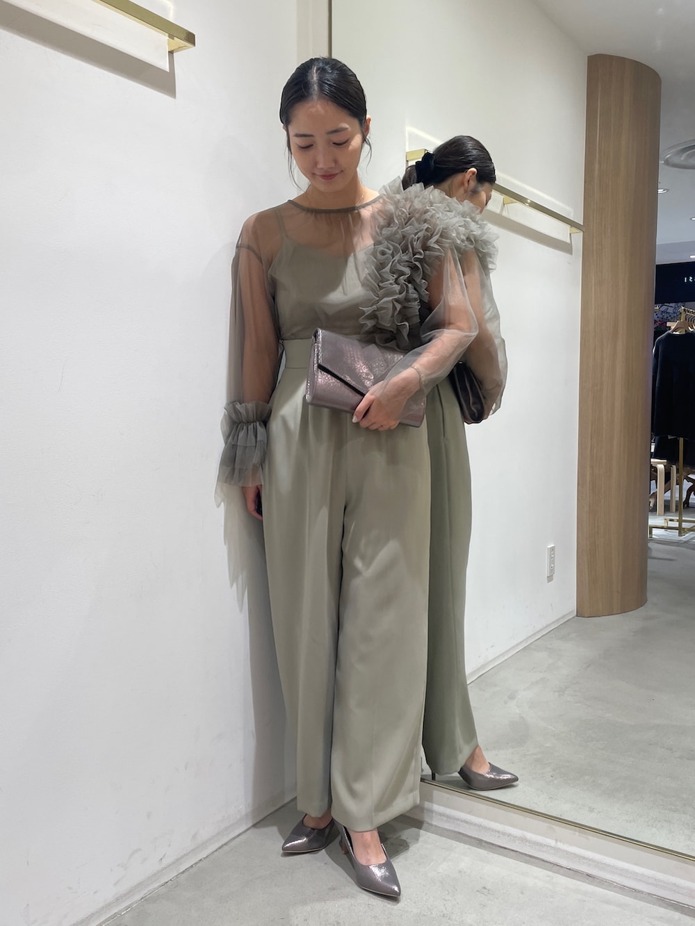 グリーン系のパンツドレス、シルバー系のハンドバッグ、シルバー系のパンプスを着用したレディースの冬コーディネートの2枚目の写真