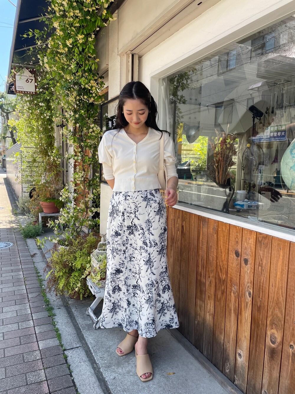 ベージュ系のハンドバッグ、ホワイト系のカーディガン/ボレロ、ブルー系のスカートを着用したレディースの春コーディネートの3枚目の写真