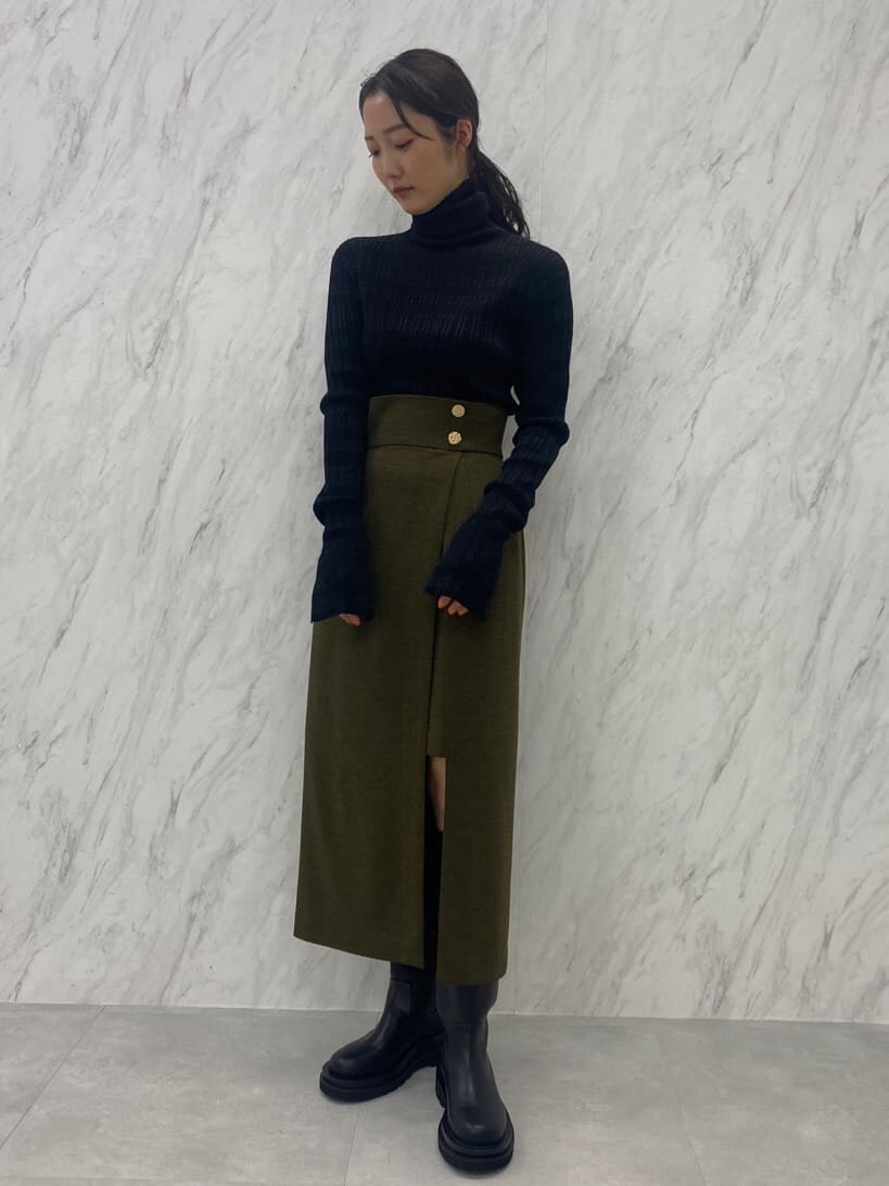 ベージュ系のスカート、ブラック系のニット/セーター、ブラック系のブーツを着用したレディースの夏コーディネートの3枚目の写真