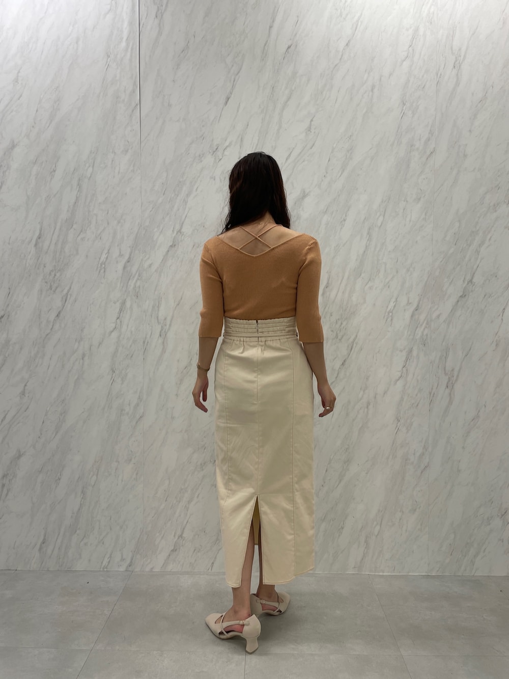 ホワイト系のパンプス、オレンジ系のニット/セーター、ホワイト系のスカートを着用したレディースの冬コーディネートの6枚目の写真