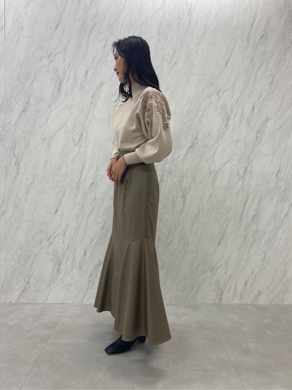 ブラック系のブーツ、ベージュ系のスカート、ホワイト系のニット/セーターを着用したレディースの秋コーディネートの4枚目の写真