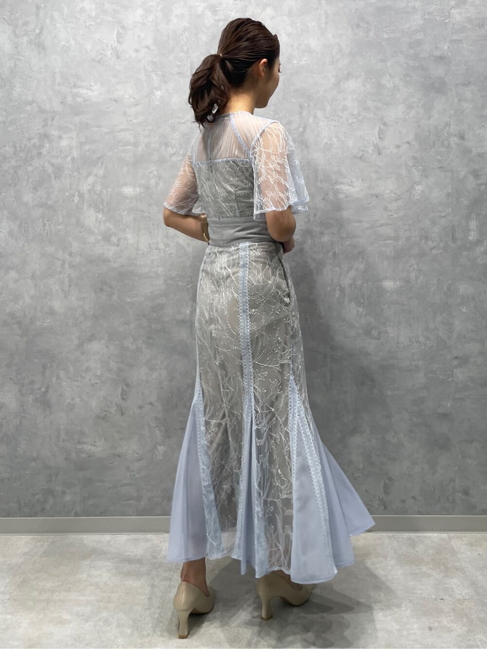 ゴールド系のクラッチバッグ、ベージュ系のパンプス、ブルー系のドレスを着用したレディースの春コーディネートの5枚目の写真