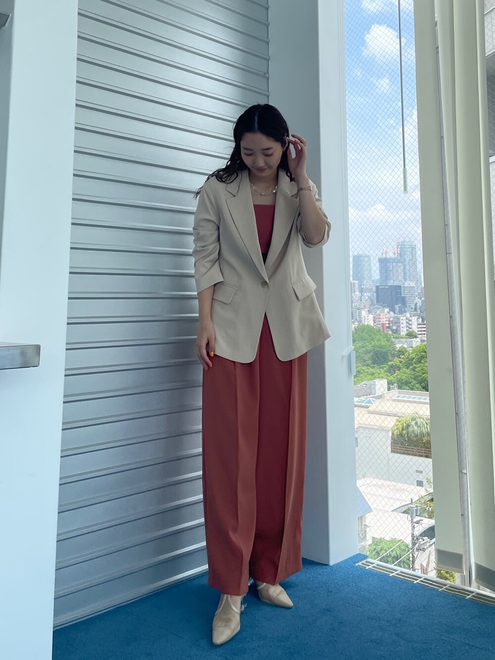 ベージュ系のパンプス、オレンジ系のパンツドレス、ベージュ系のテーラードジャケットを着用したレディースの夏コーディネートの3枚目の写真