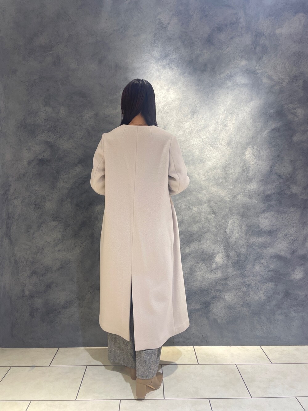 ホワイト系のノーカラーコート、グレー系のニット/セーター、ブラック系のその他パンツを着用したレディースの秋コーディネートの4枚目の写真