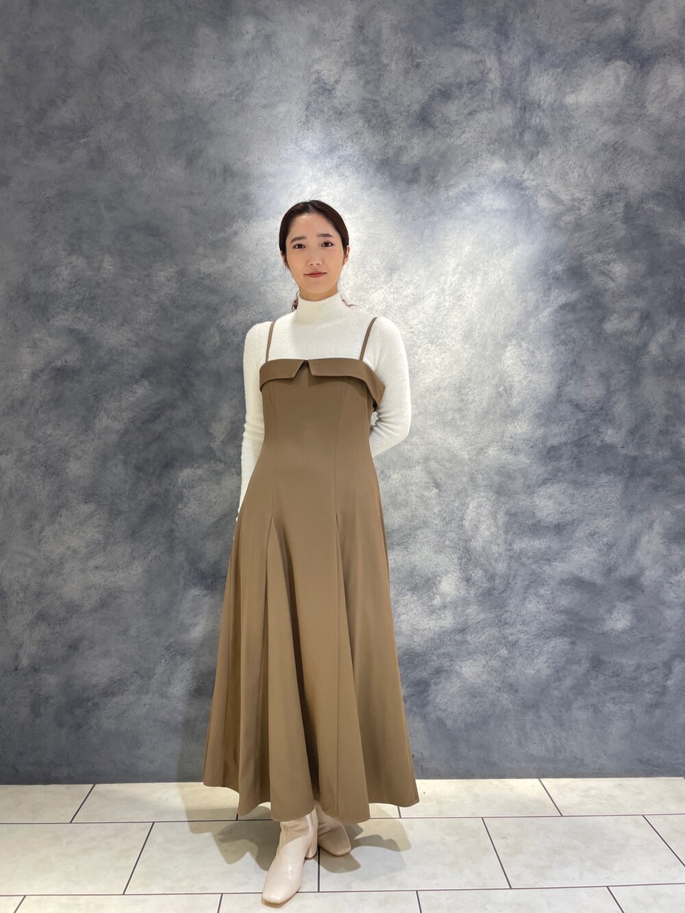 ベージュ系のワンピース、ホワイト系のニット/セーター、ホワイト系のブーツを着用したレディースの冬コーディネートの2枚目の写真