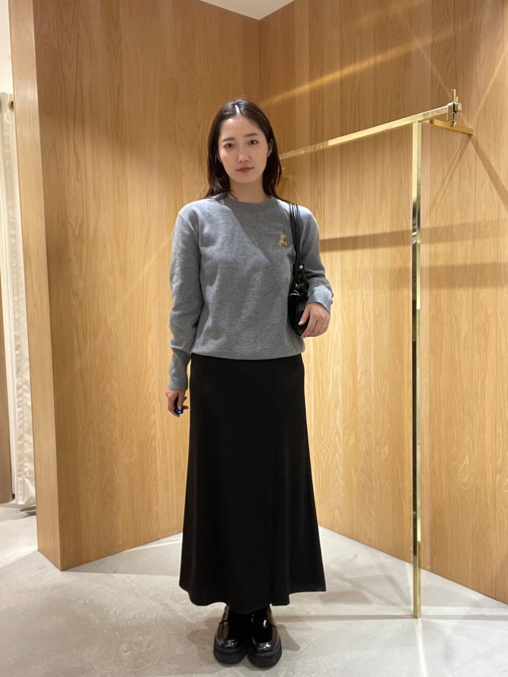 グレー系のニット/セーター、ブラック系のスカート、ブラック系のローファーを着用したレディースの秋コーディネートの2枚目の写真