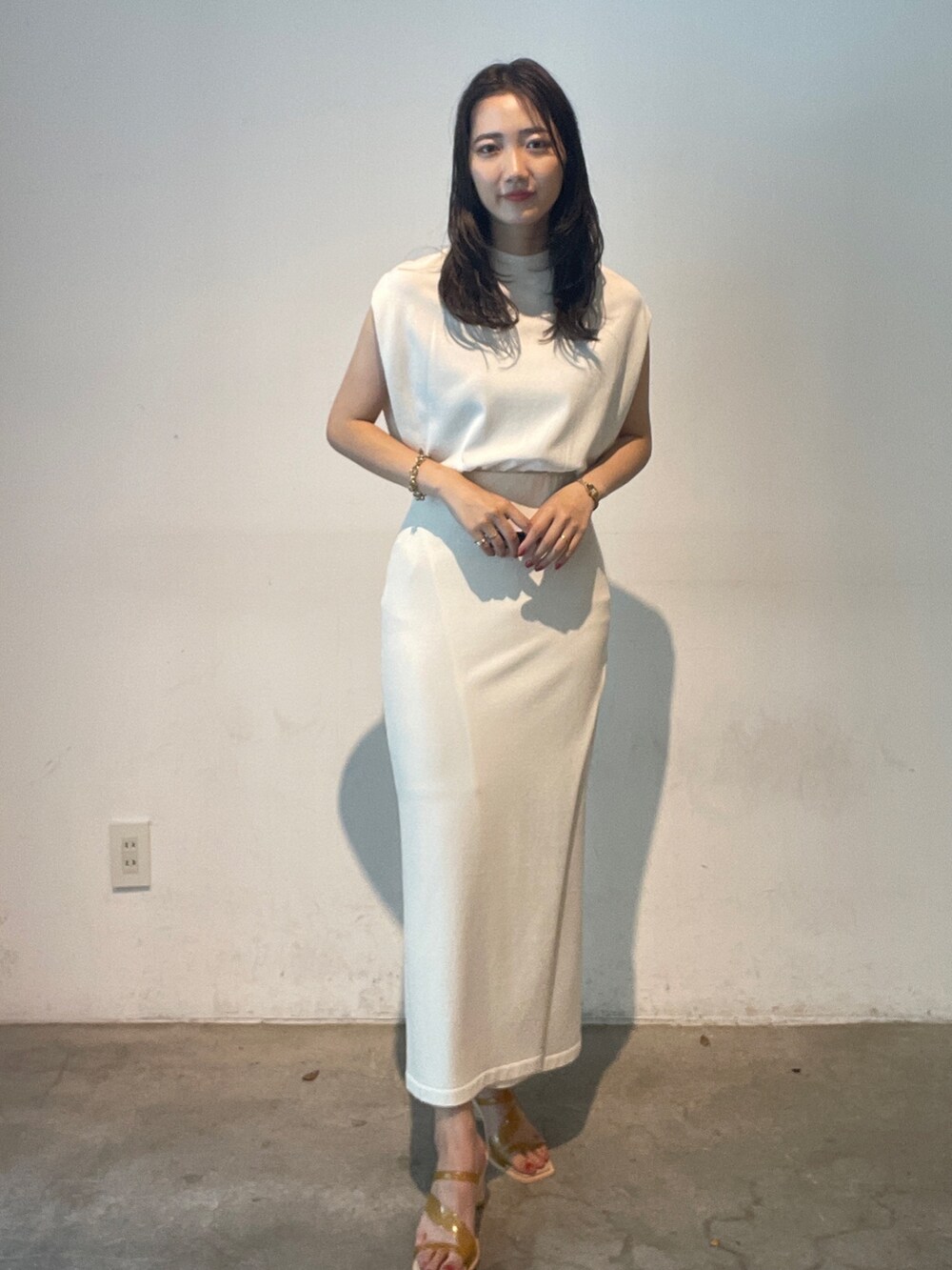 ホワイト系のスカート、ホワイト系のニット/セーター、イエロー系のサンダルを着用したレディースの夏コーディネートの2枚目の写真