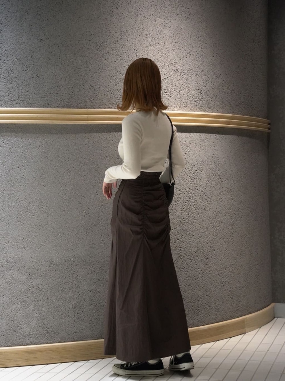 ブラック系のショルダーバッグ、ブラウン系のスカート、ホワイト系のニット/セーターを着用したレディースの秋コーディネートの4枚目の写真