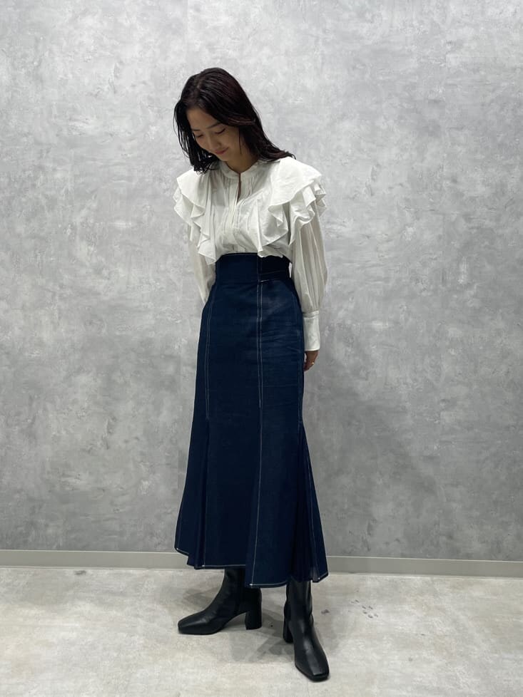 ブラック系のブーツ、ブルー系のスカート、ホワイト系のシャツ/ブラウスを着用したレディースの秋コーディネートの3枚目の写真
