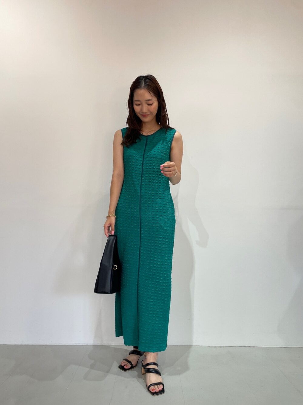 グリーン系のワンピース、ブラック系のサンダル、ブラック系のハンドバッグを着用したレディースの夏コーディネートの2枚目の写真