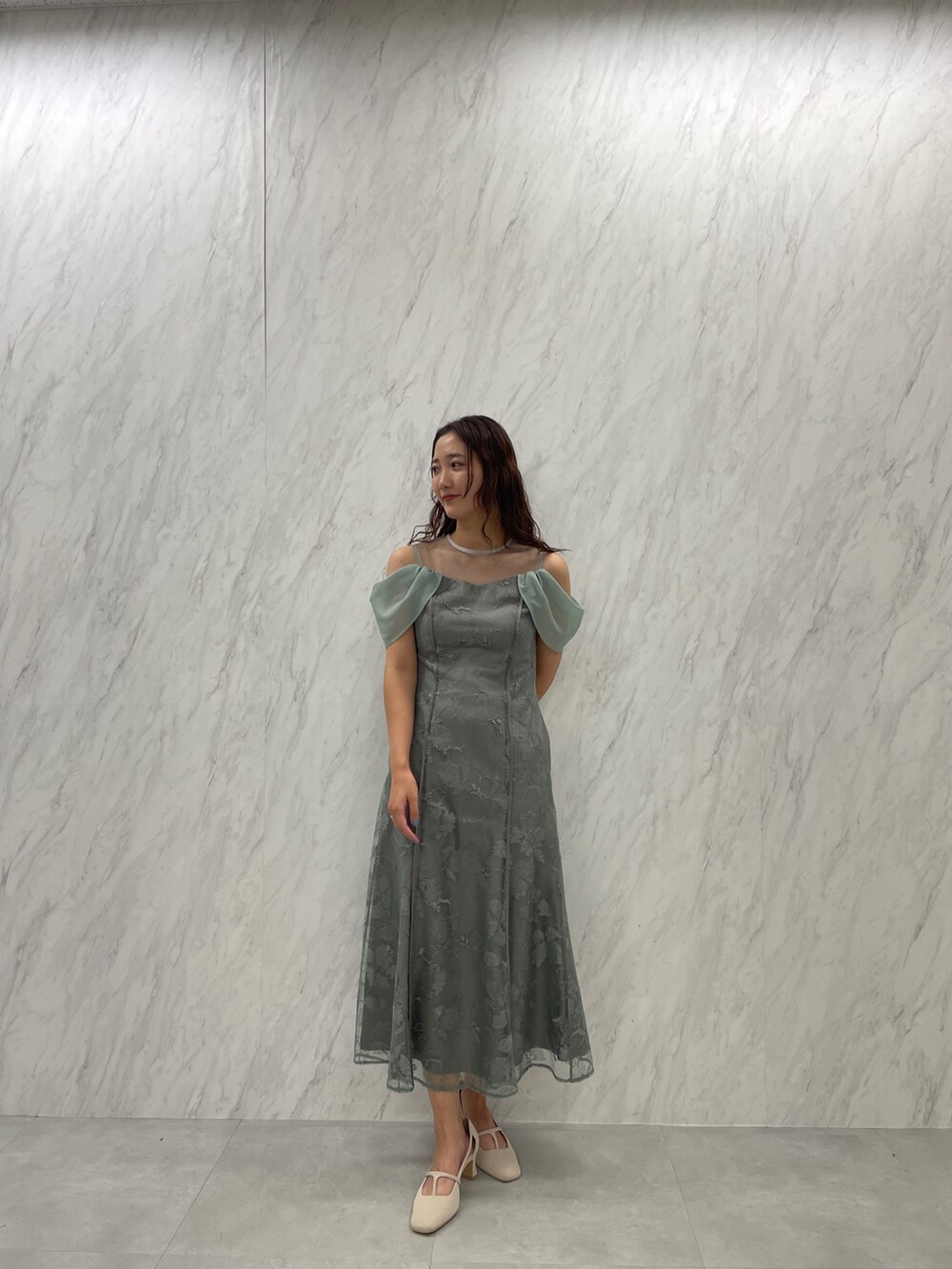 ホワイト系のパンプス、グリーン系のドレスを着用したレディースの冬コーディネートの2枚目の写真