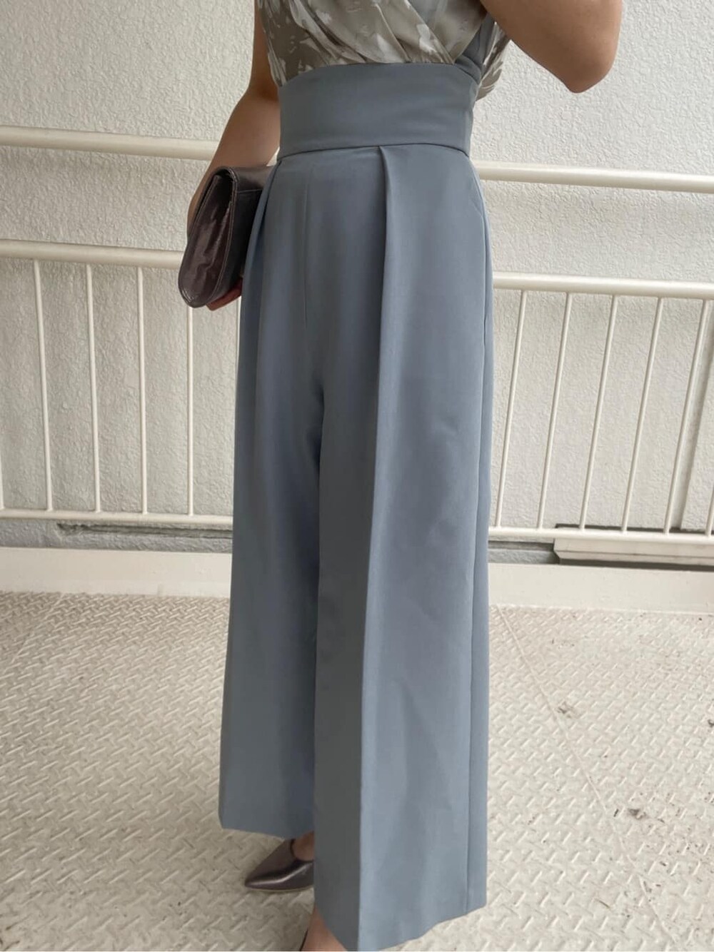 シルバー系のパンプス、シルバー系のクラッチバッグ、ブルー系のパンツドレスを着用したレディースの春コーディネートの7枚目の写真
