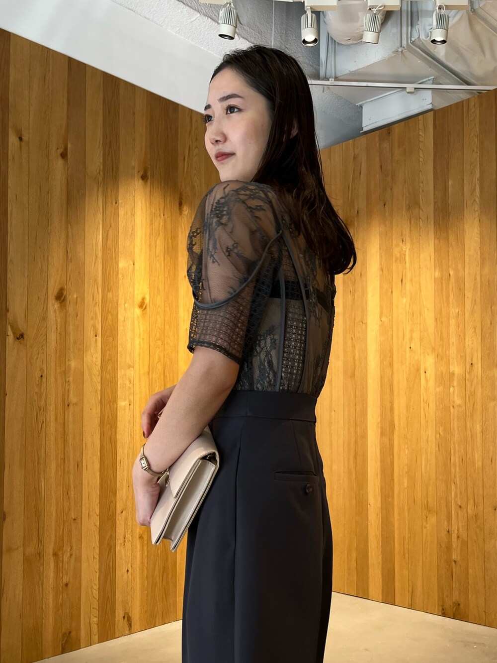 グレー系のパンツドレス、ベージュ系のクラッチバッグ、ベージュ系のパンプスを着用したレディースの冬コーディネートの7枚目の写真