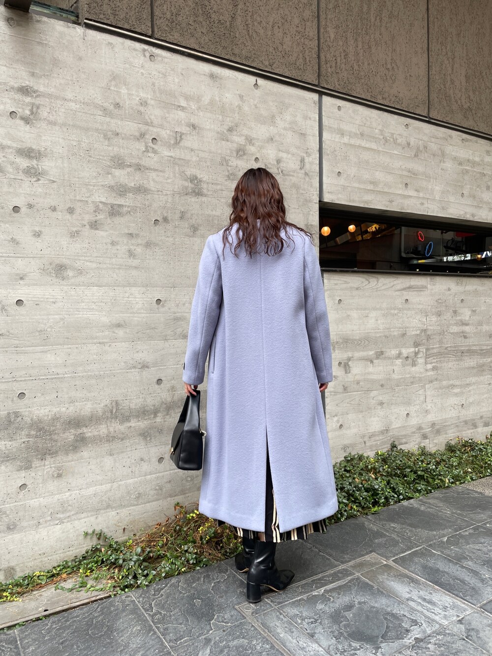 ブルー系のノーカラーコート、ブラック系のワンピース、ブラック系のブーツを着用したレディースの冬コーディネートの5枚目の写真