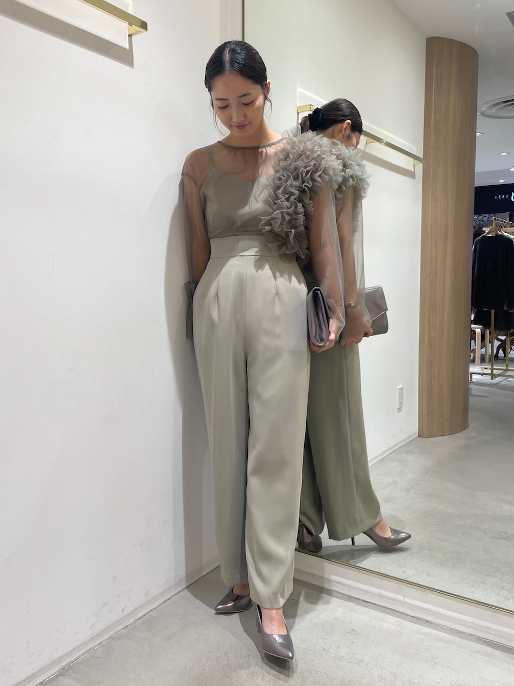 グリーン系のパンツドレス、シルバー系のハンドバッグ、シルバー系のパンプスを着用したレディースの冬コーディネートの3枚目の写真