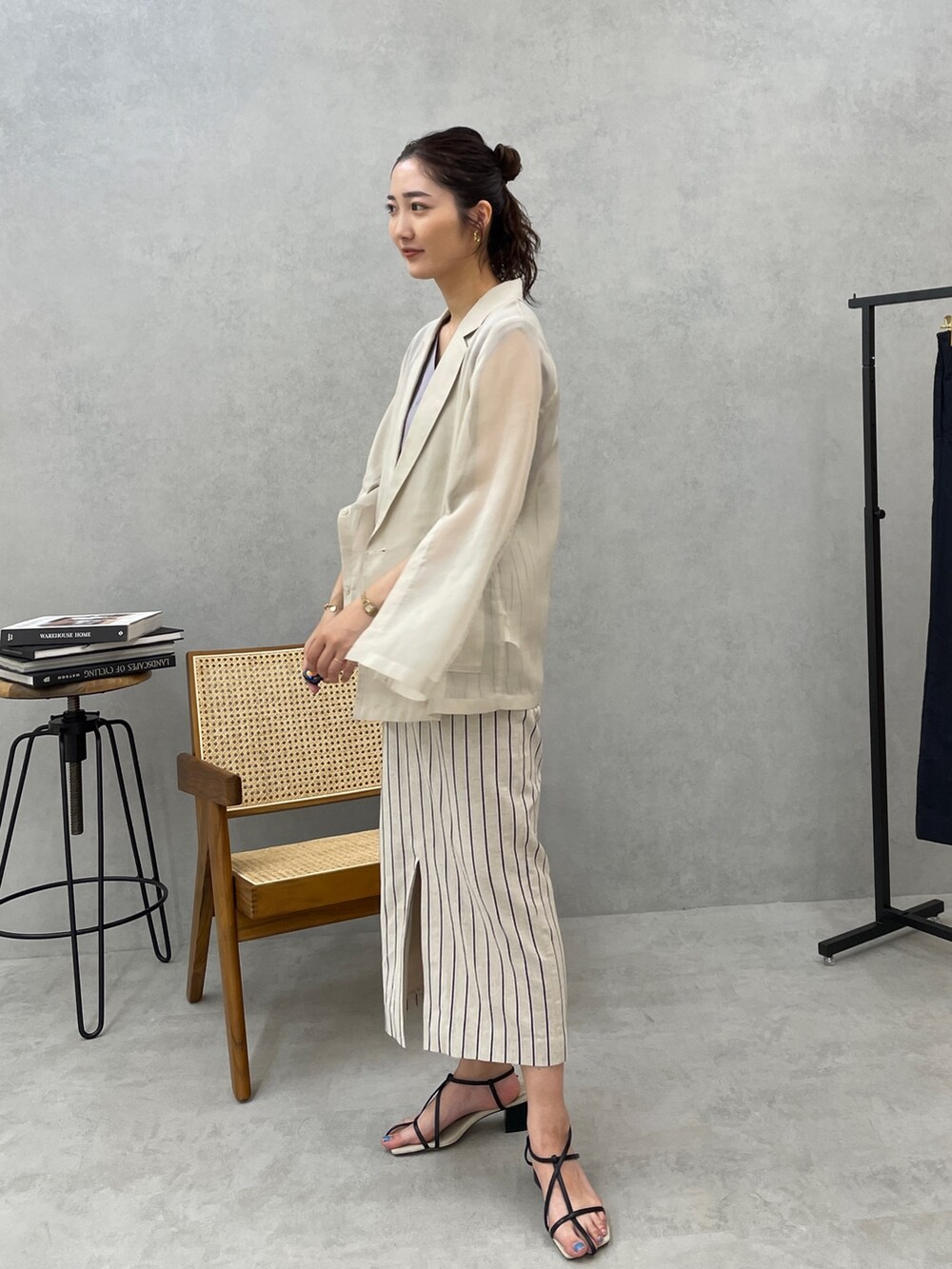 グレー系のスカート、ホワイト系のテーラードジャケット、ブルー系のニット/セーターを着用したレディースの春コーディネートの2枚目の写真