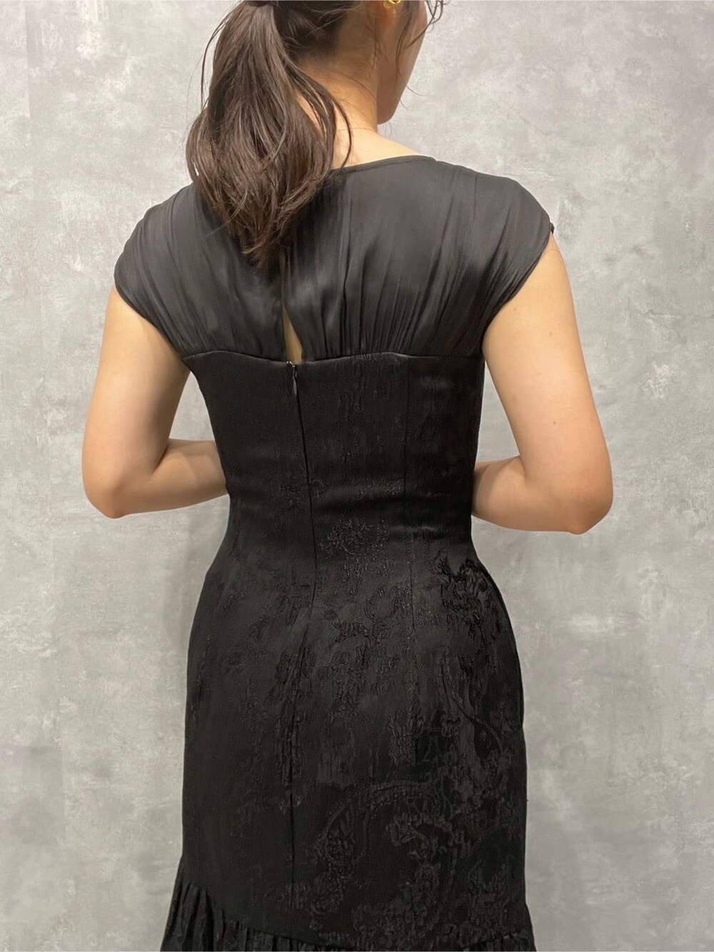 シルバー系のパンプス、シルバー系のクラッチバッグ、ブラック系のドレスを着用したレディースの夏コーディネートの7枚目の写真
