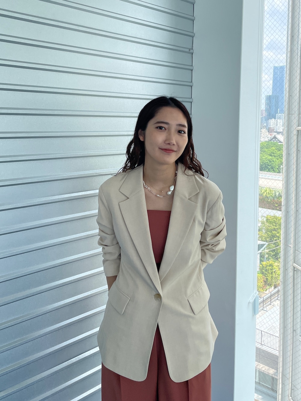 ベージュ系のパンプス、オレンジ系のパンツドレス、ベージュ系のテーラードジャケットを着用したレディースの夏コーディネートの5枚目の写真