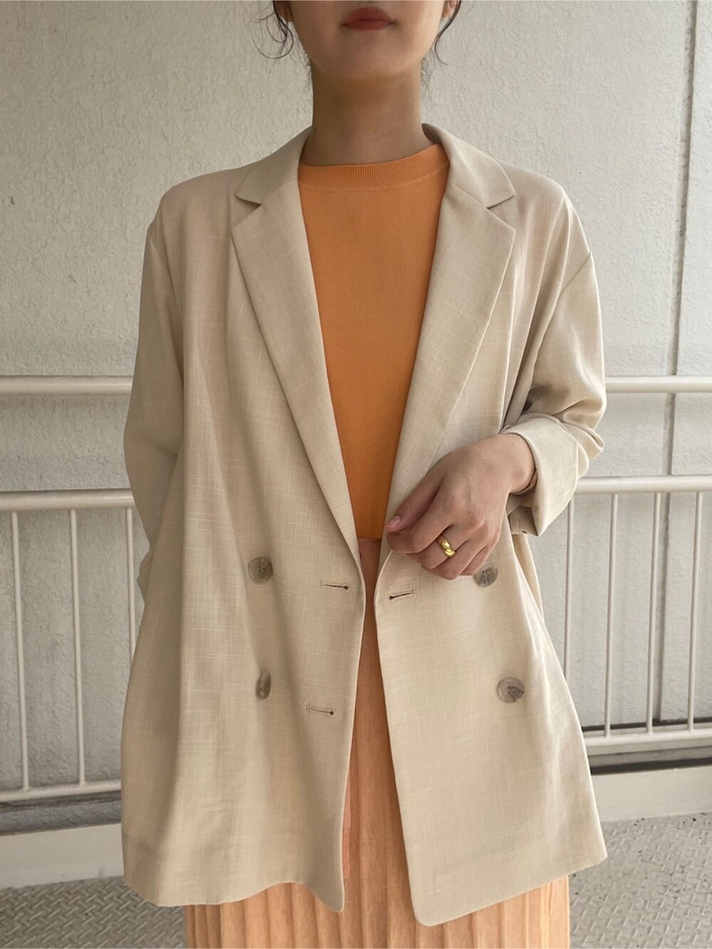 ベージュ系のブーツ、ベージュ系のテーラードジャケット、オレンジ系のワンピースを着用したレディースの春コーディネートの7枚目の写真