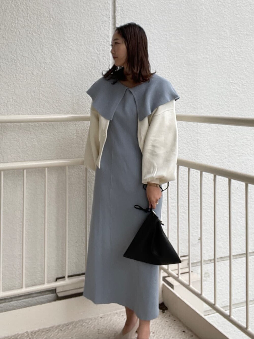 ブルー系のワンピース、ブラック系のハンドバッグ、ホワイト系のパンプスを着用したレディースの冬コーディネートの6枚目の写真