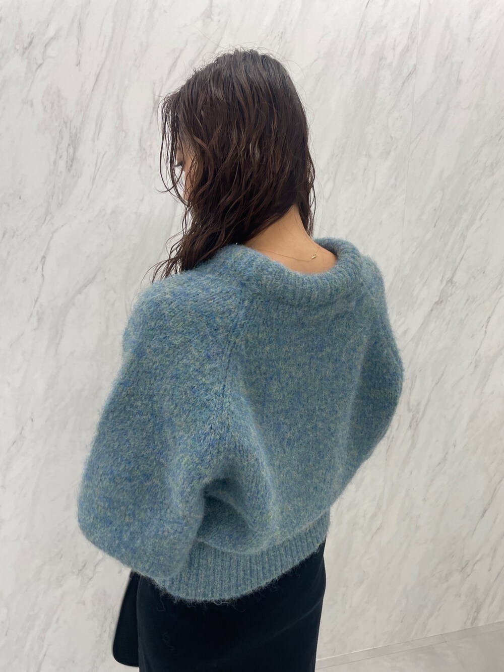 グリーン系のニット/セーター、ブラック系のブーツ、ブラック系のスカートを着用したレディースの冬コーディネートの9枚目の写真