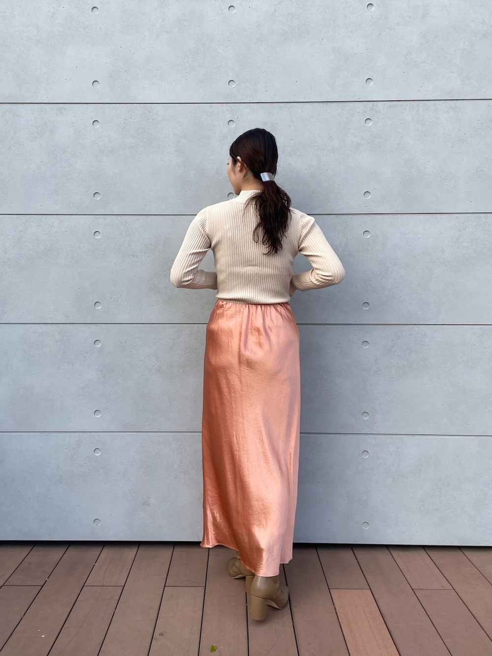 ホワイト系のニット/セーター、オレンジ系のスカート、ベージュ系のブーツを着用したレディースの冬コーディネートの6枚目の写真