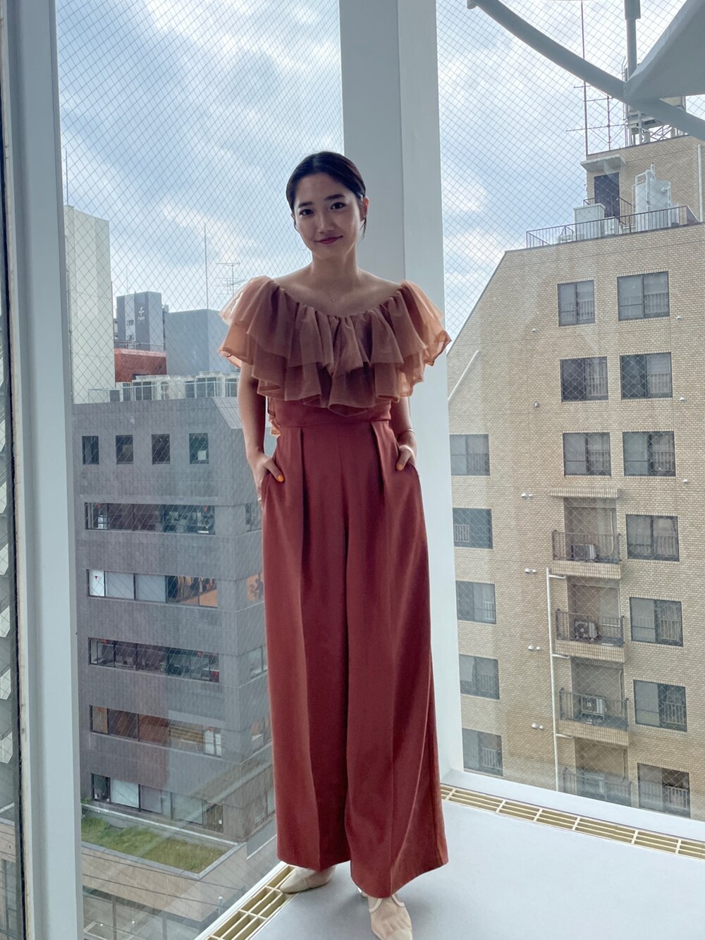 ベージュ系のパンプス、オレンジ系のパンツドレス、ベージュ系のテーラードジャケットを着用したレディースの夏コーディネートの7枚目の写真