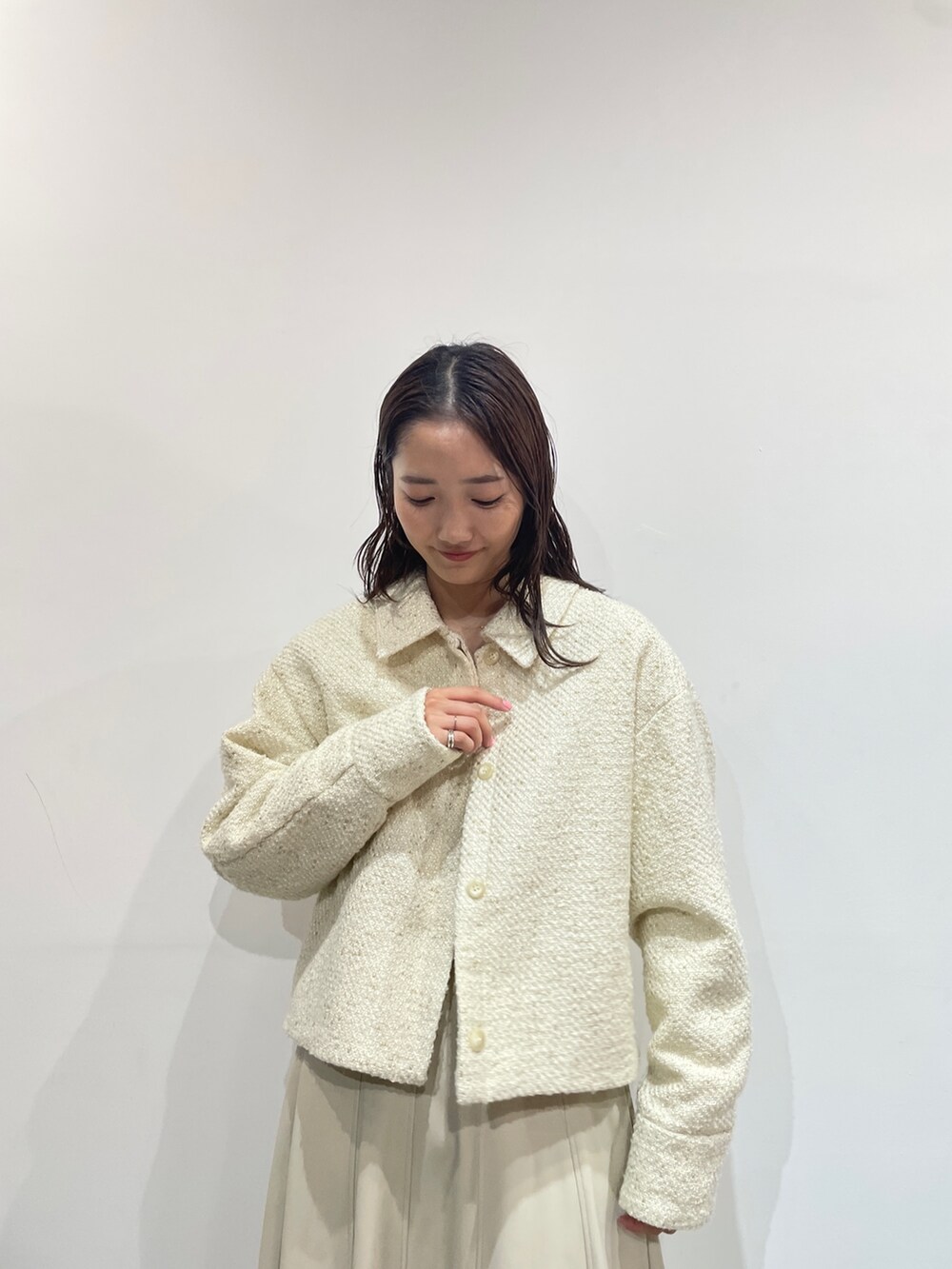 オレンジ系のニット/セーター、ホワイト系のスカート、ベージュ系のブーツを着用したレディースの秋コーディネートの2枚目の写真