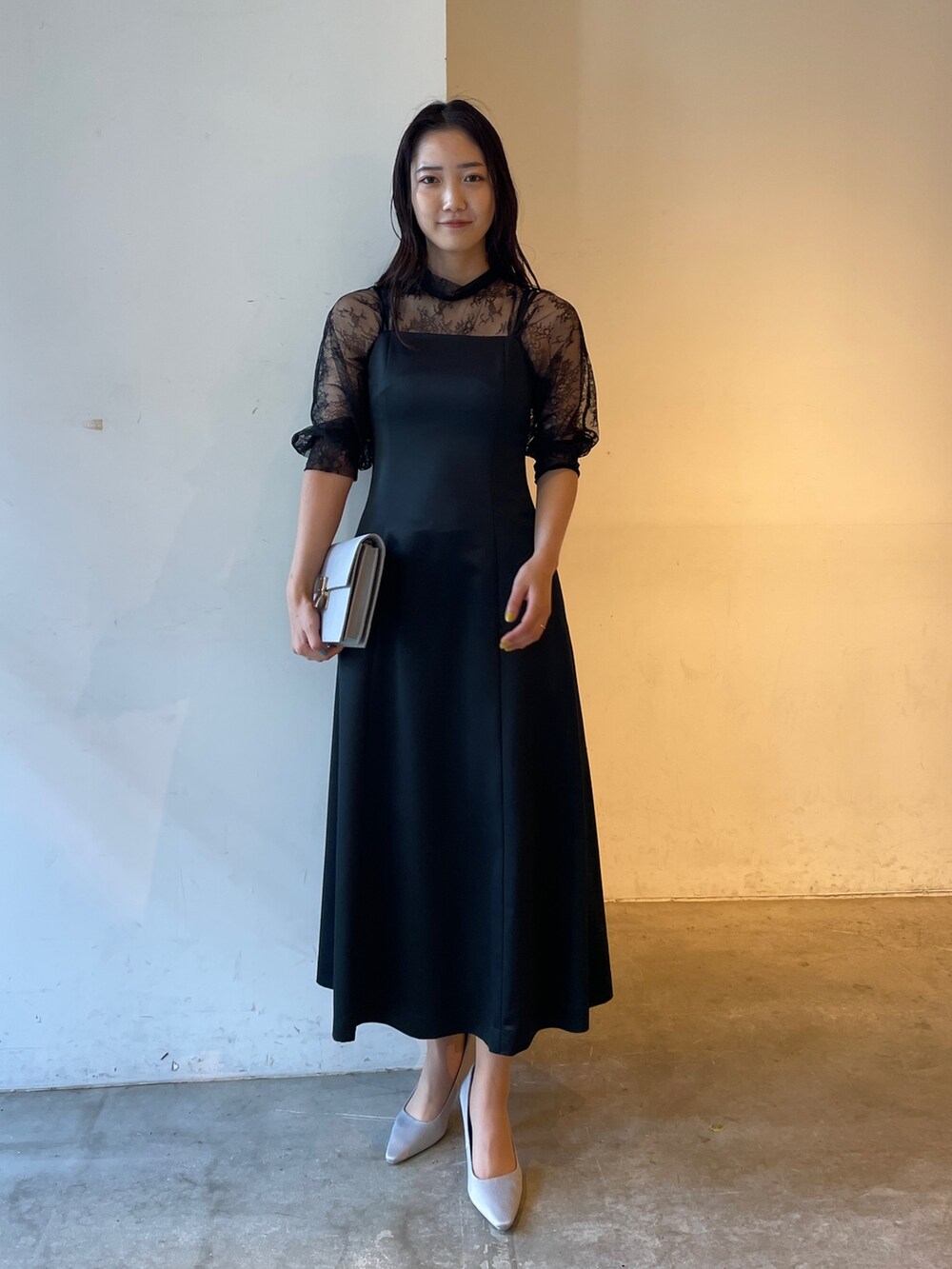 グレー系のパンプス、ブラック系のドレス、グレー系のクラッチバッグを着用したレディースの冬コーディネートの6枚目の写真