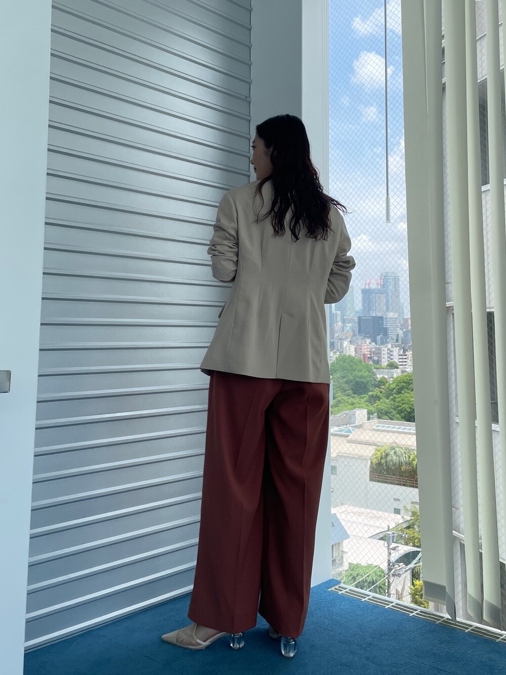 ベージュ系のパンプス、オレンジ系のパンツドレス、ベージュ系のテーラードジャケットを着用したレディースの夏コーディネートの4枚目の写真