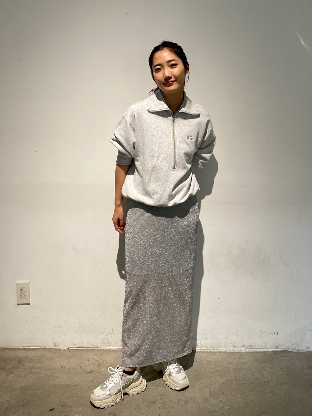 シルバー系のスカート、グレー系のスウェット、ホワイト系のスニーカーを着用したレディースの秋コーディネートの3枚目の写真