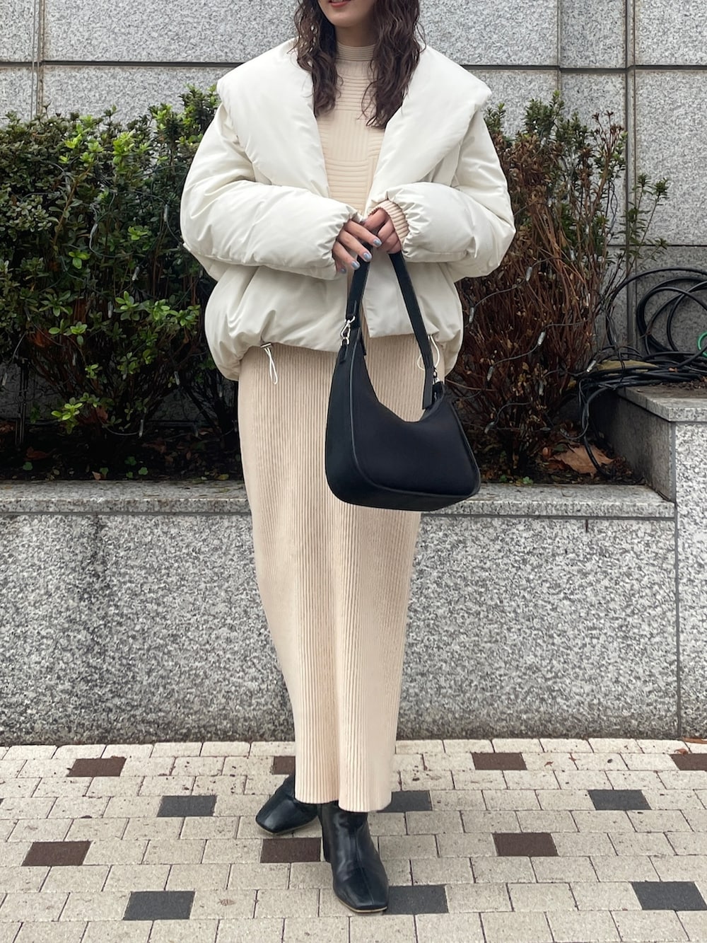 ホワイト系のダウンジャケット/コート、ベージュ系のワンピース、ブラック系のブーツを着用したレディースの冬コーディネートの6枚目の写真