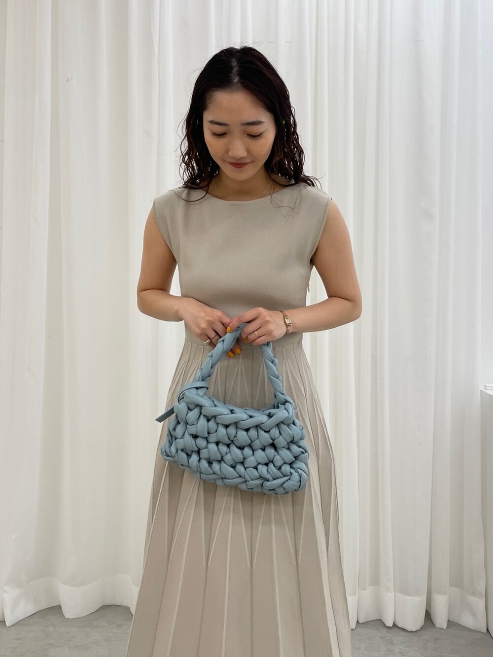 ブラック系のサンダル、ブルー系のハンドバッグ、ベージュ系のワンピースを着用したレディースの春コーディネートの8枚目の写真