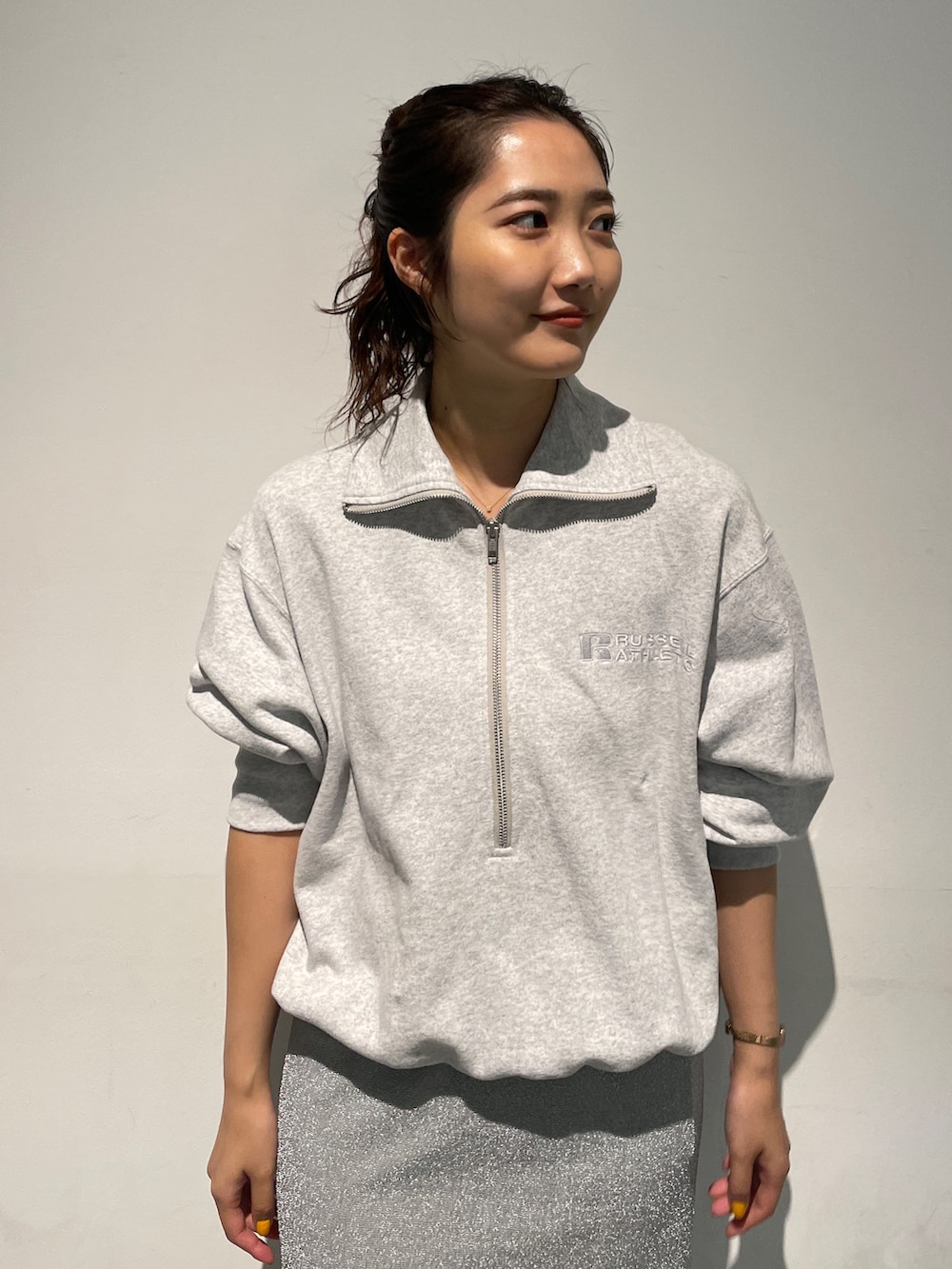 シルバー系のスカート、グレー系のスウェット、ホワイト系のスニーカーを着用したレディースの秋コーディネートの7枚目の写真