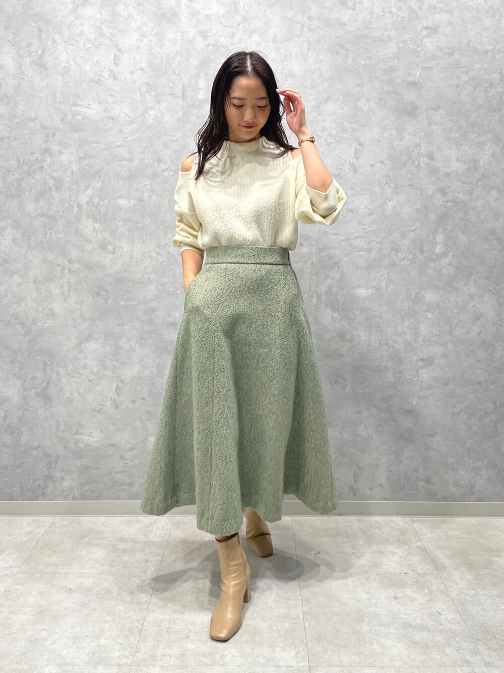 ベージュ系のブーツ、ホワイト系のニット/セーター、グリーン系のスカートを着用したレディースの冬コーディネートの4枚目の写真