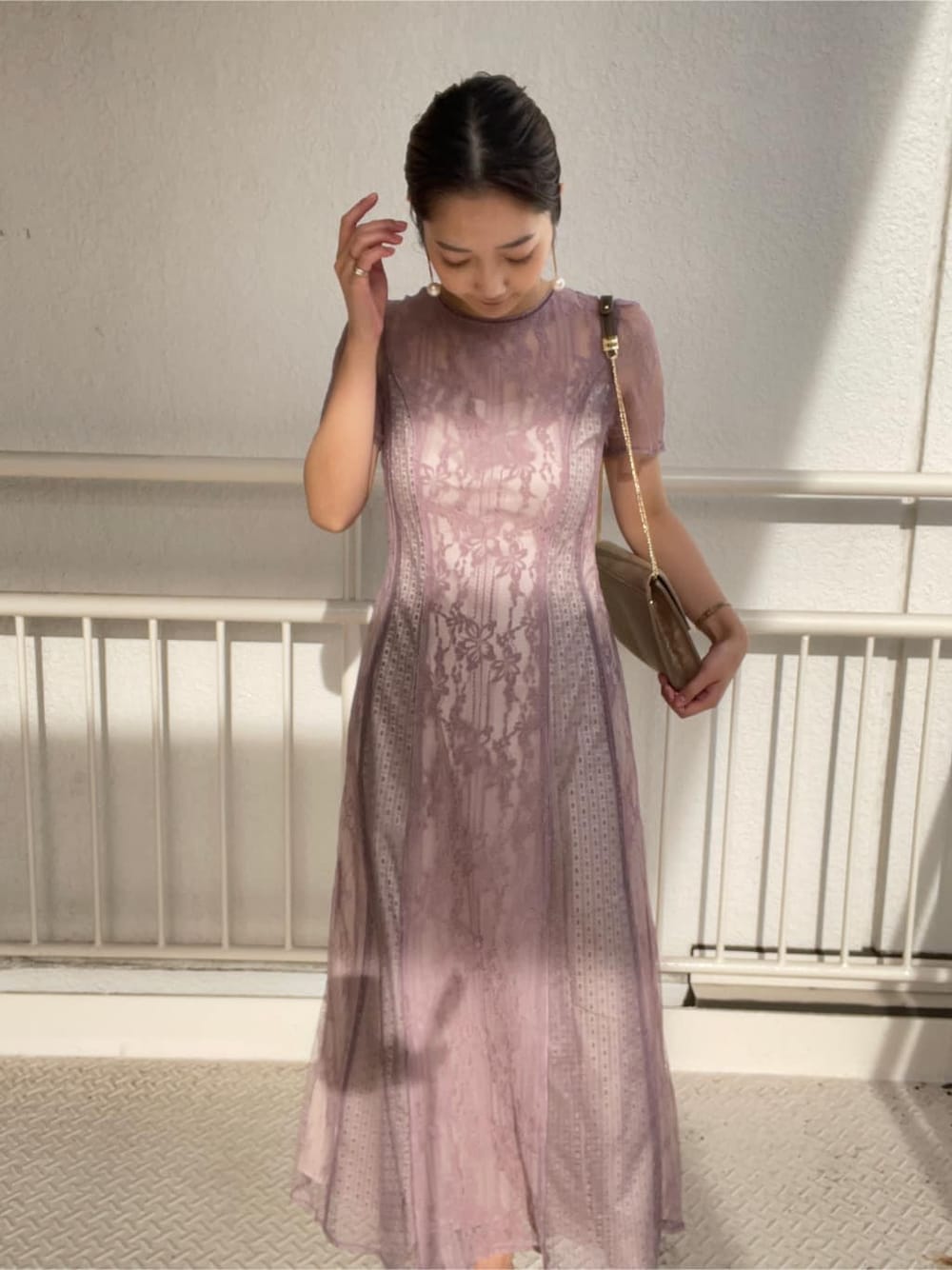 ゴールド系のパンプス、ゴールド系のクラッチバッグ、パープル系のドレスを着用したレディースの冬コーディネートの3枚目の写真