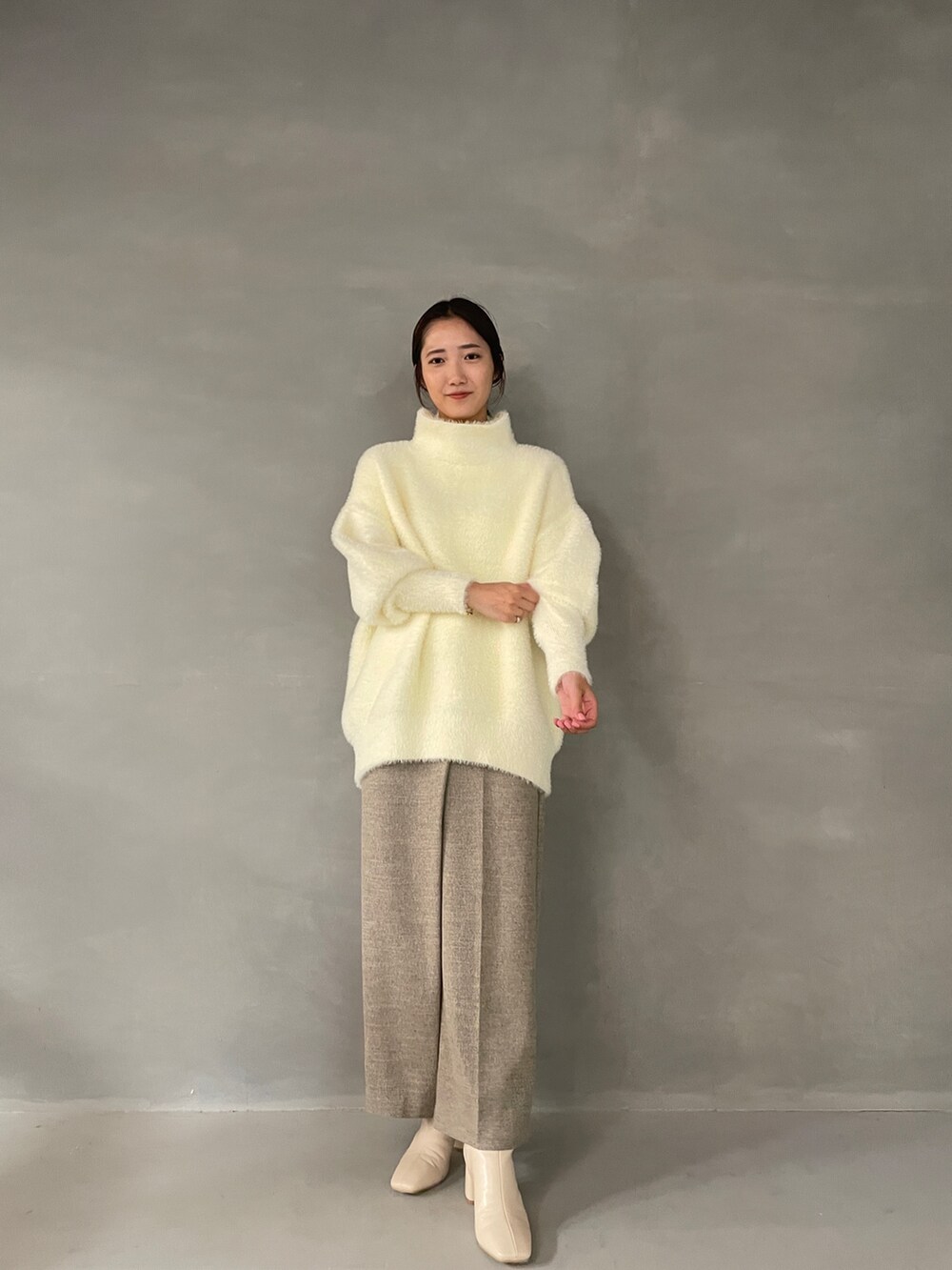 ホワイト系のニット/セーター、ベージュ系のその他パンツ、ホワイト系のブーツを着用したレディースの夏コーディネートの2枚目の写真