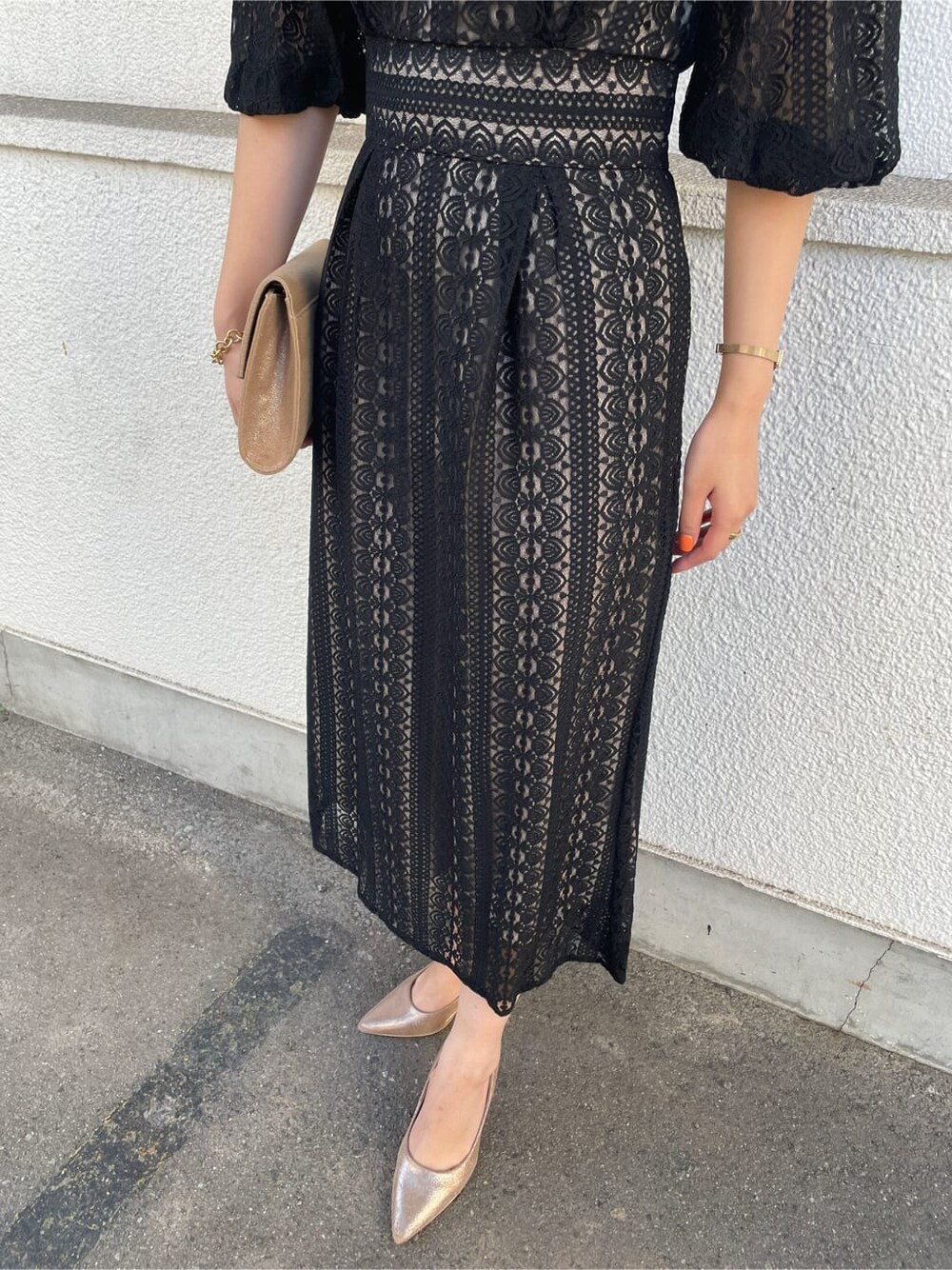 ゴールド系のパンプス、ゴールド系のクラッチバッグ、ブラック系のドレスを着用したレディースの冬コーディネートの7枚目の写真