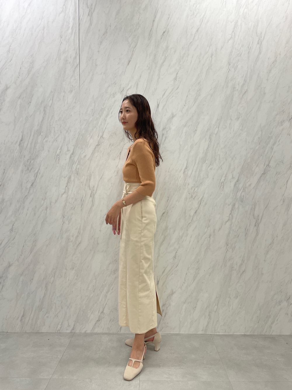 ホワイト系のパンプス、オレンジ系のニット/セーター、ホワイト系のスカートを着用したレディースの冬コーディネートの5枚目の写真