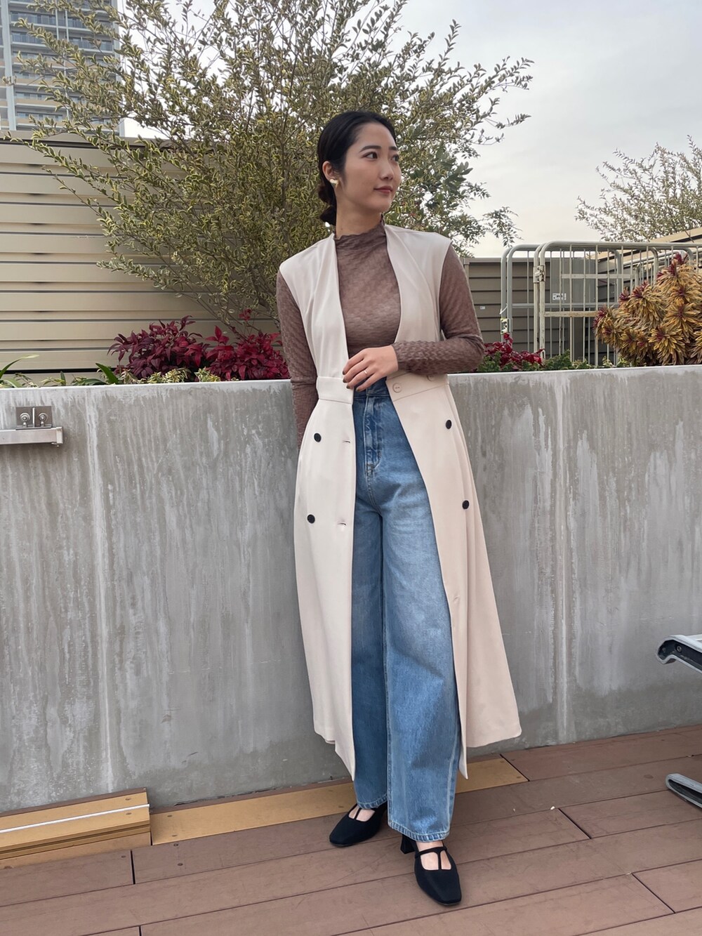 ホワイト系のトレンチコート、ブルー系のデニムパンツ、ブラック系のパンプスを着用したレディースの冬コーディネートの4枚目の写真