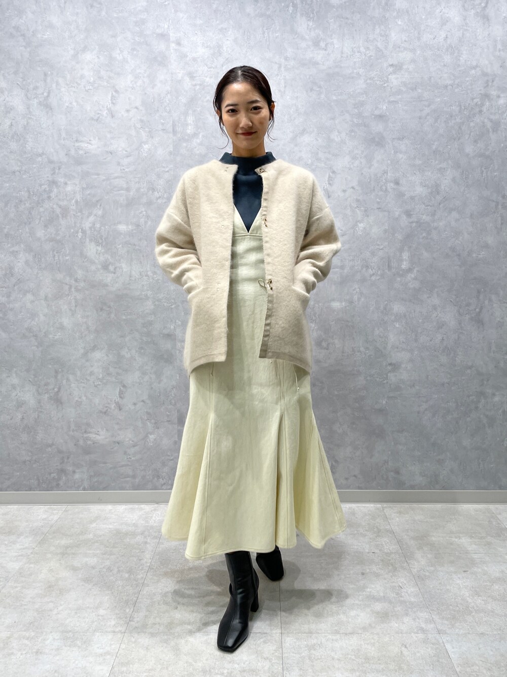 グリーン系のニット/セーター、ホワイト系のカーディガン/ボレロ、ブラック系のブーツを着用したレディースの冬コーディネートの2枚目の写真