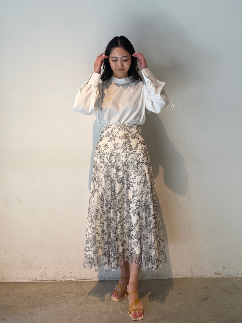 ホワイト系のシャツ/ブラウス、ホワイト系のスカート、イエロー系のサンダルを着用したレディースの冬コーディネートの2枚目の写真