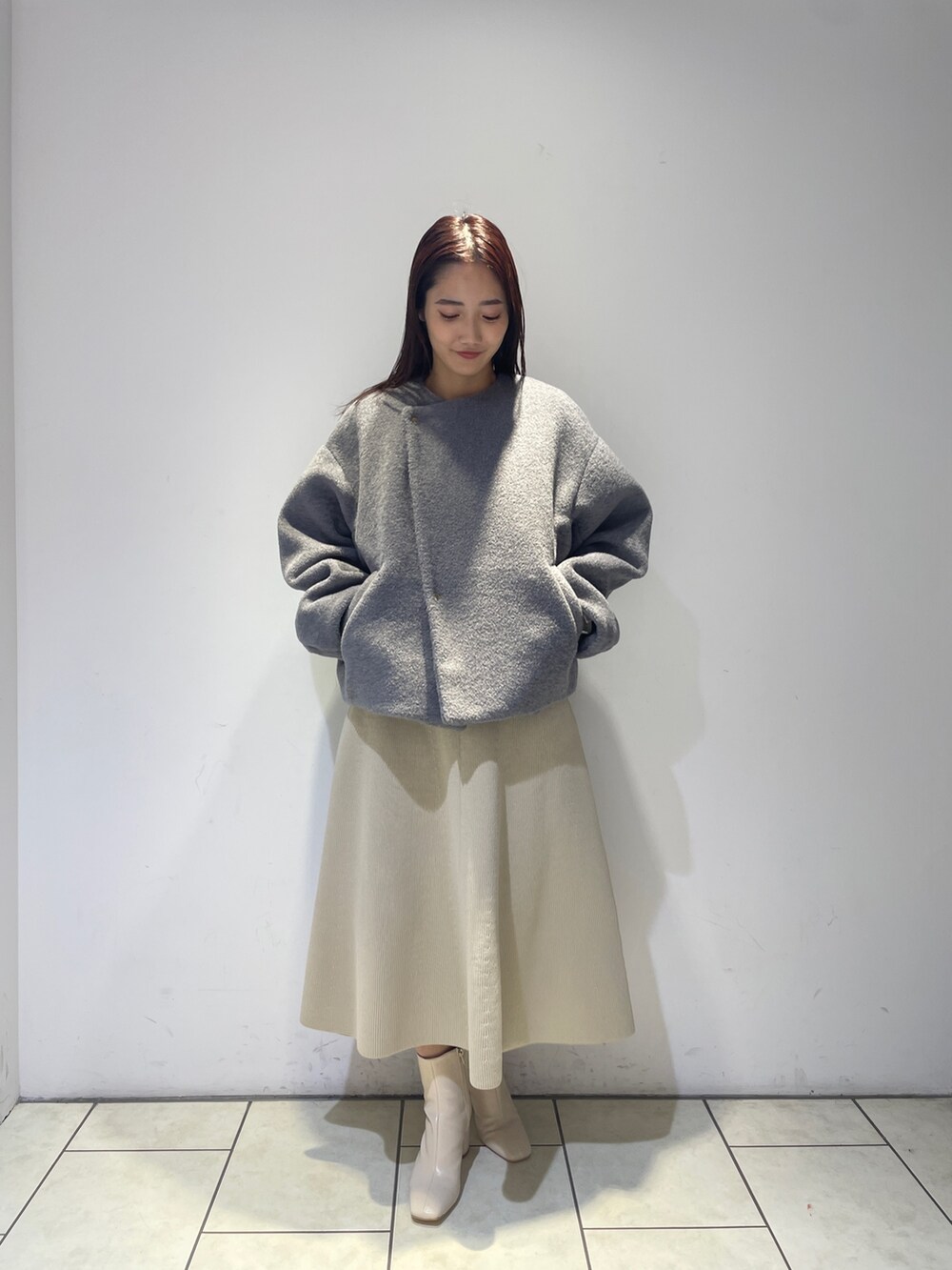 ホワイト系のニット/セーター、ホワイト系のジャンパースカート、ホワイト系のブーツを着用したレディースの秋コーディネートの6枚目の写真