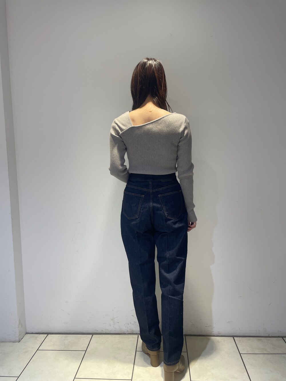 ホワイト系のノーカラーコート、グレー系のニット/セーター、ブルー系のデニムパンツを着用したレディースの秋コーディネートの7枚目の写真