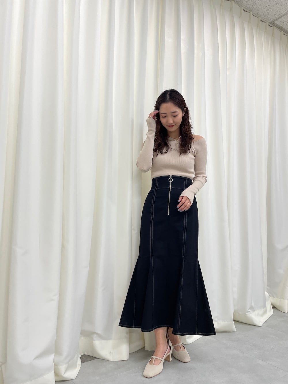 ブラック系のスカート、ベージュ系のニット/セーター、ホワイト系のパンプスを着用したレディースの冬コーディネートの4枚目の写真