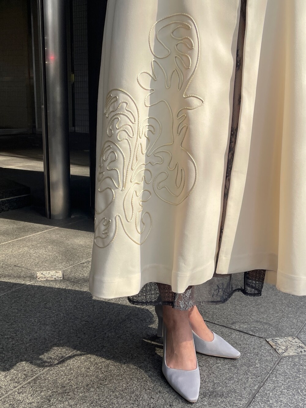 グレー系のドレス、グレー系のパンプス、ホワイト系のトレンチコートを着用したレディースの冬コーディネートの10枚目の写真