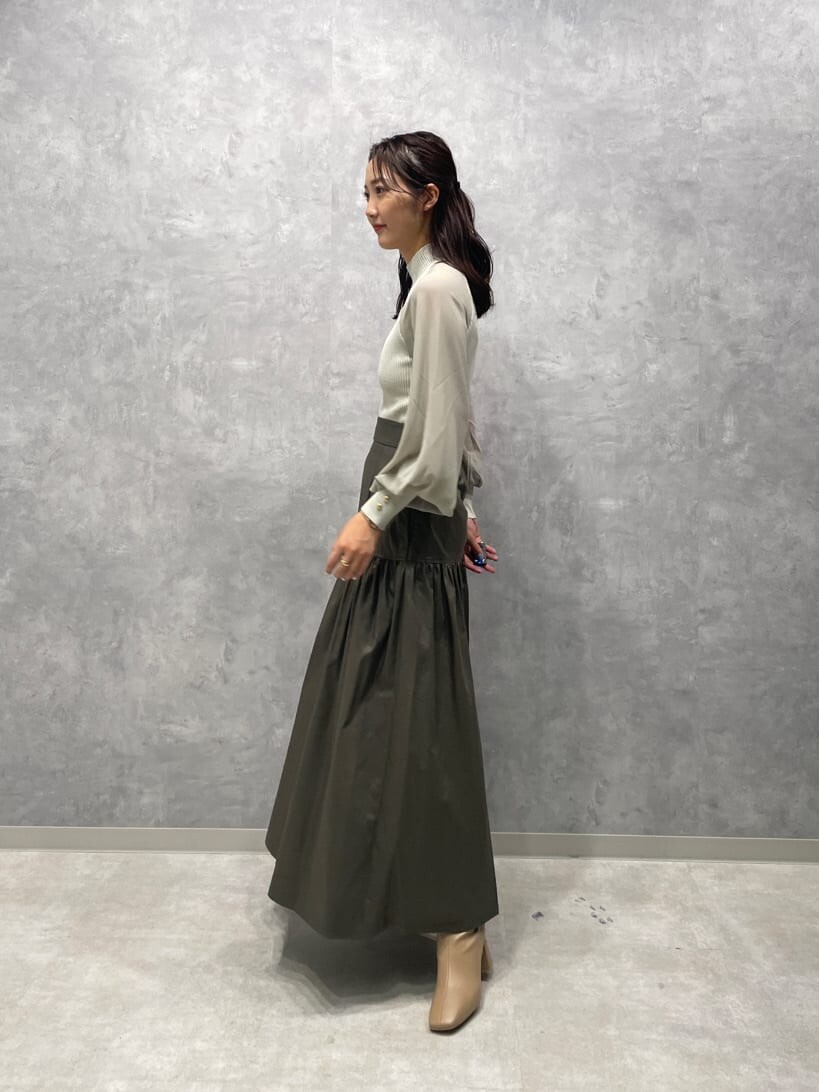 ベージュ系のスカート、ベージュ系のブーツ、グリーン系のニット/セーターを着用したレディースの夏コーディネートの5枚目の写真