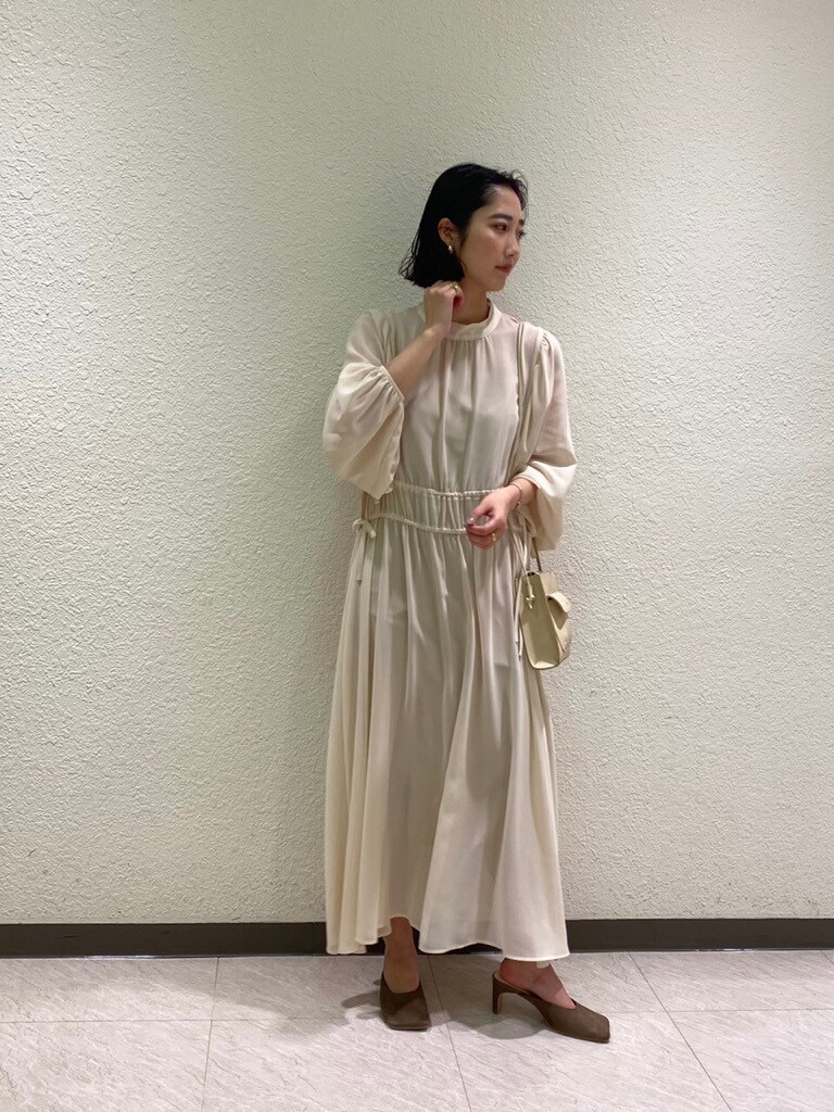 ベージュ系のハンドバッグ、ベージュ系のサンダル、ホワイト系のワンピースを着用したレディースの冬コーディネートの3枚目の写真